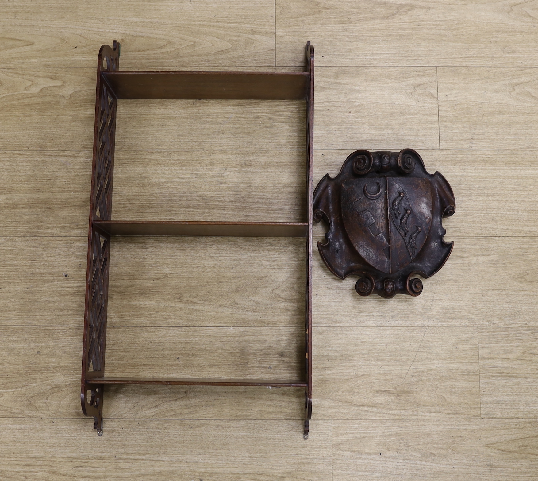 A Chippendale style open hanging shelf and an 18th/19th century carved mahogany armorial shield, shelves 80cm x 40cm